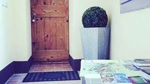A wooden door, a potted plant, a tiled floor, and a table with papers. - B&B Relais Druda (Cagli)
