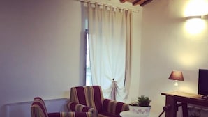 A cozy living room with striped armchairs, a small table with a plant, and a lamp. - B&B Relais Druda (Cagli)