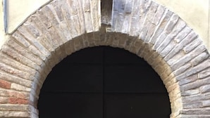 A black arched door with a metal handle, set in a stone wall. - B&B Relais Druda (Cagli)