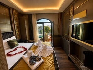 Quarto de hotel com cama, televisão e vista da cidade.