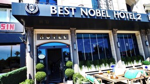 Het uiterlijk van Best Nobel Hotel 2, met een rode loper om bezoekers te verwelkomen, een bord met de naam van het hotel, en een uitzicht op de ingang.