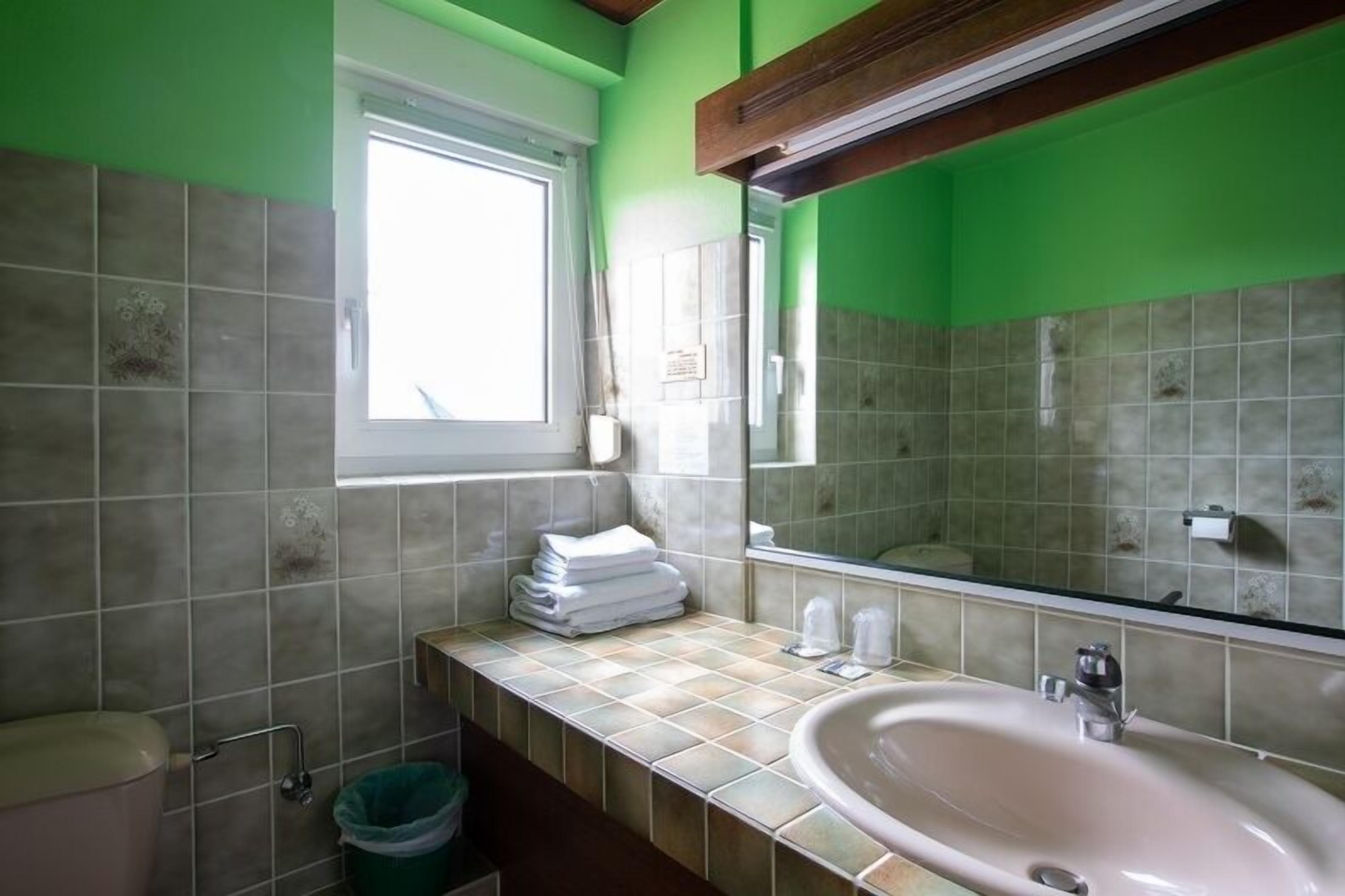 Een badkamer met een wastafel, spiegel en betegelde wanden.