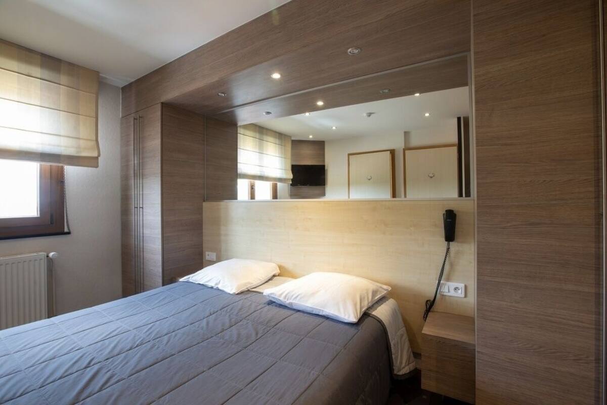 Un dormitorio moderno con una cama grande, un teléfono en la mesita de noche y un espejo sobre la cama.