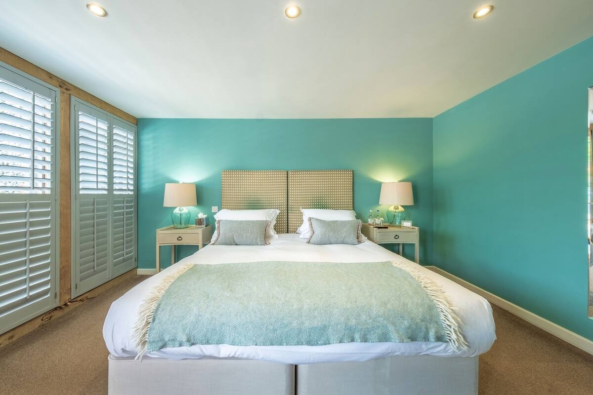 A bedroom with a bed, two bedside tables, and a window with blinds.