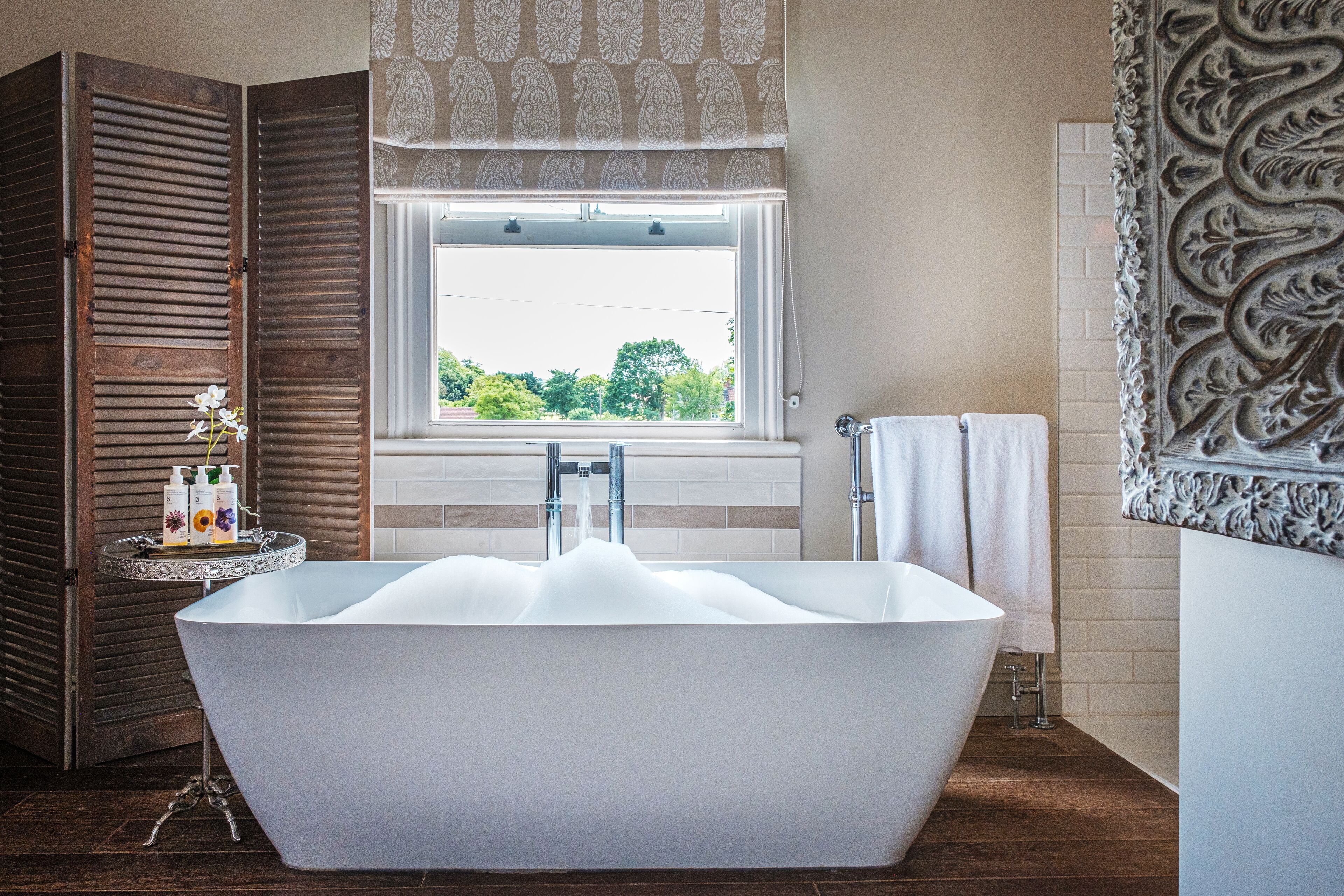 Un baño moderno con una bañera independiente, un ventanal con vistas y un panel decorativo en la pared.