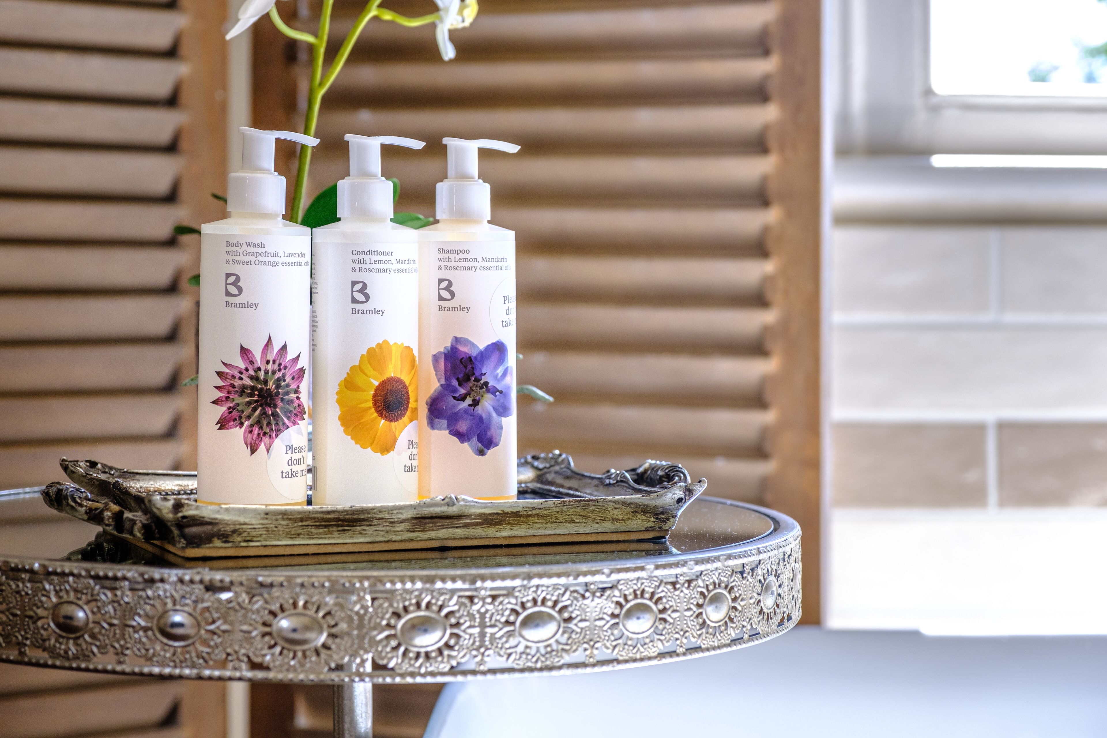 Drei Flaschen Bramley Duschgel, Conditioner und Shampoo auf einer verzierten Silbertablett.