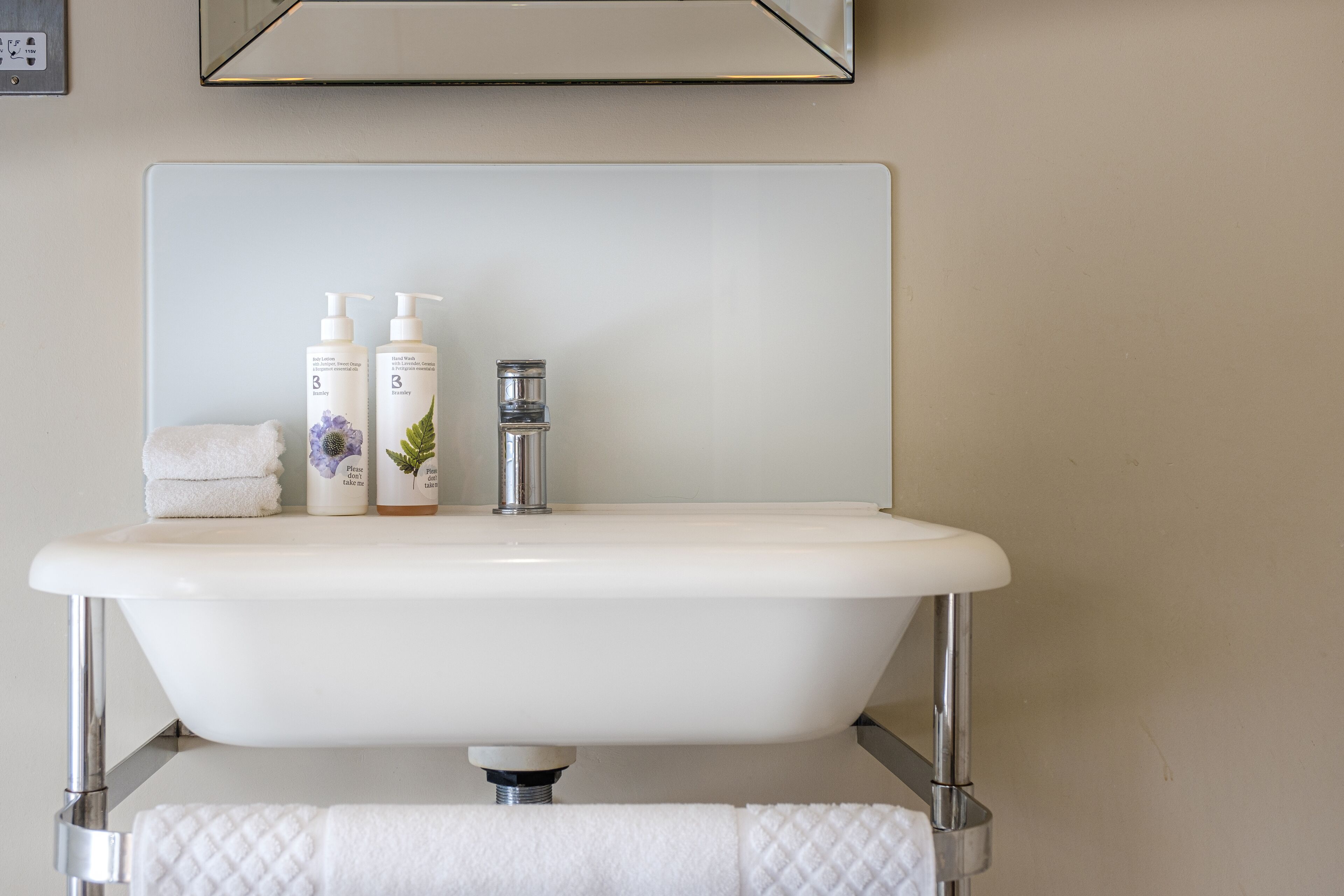 A bathroom with a white sink, two bottles of shampoo, and a towel.