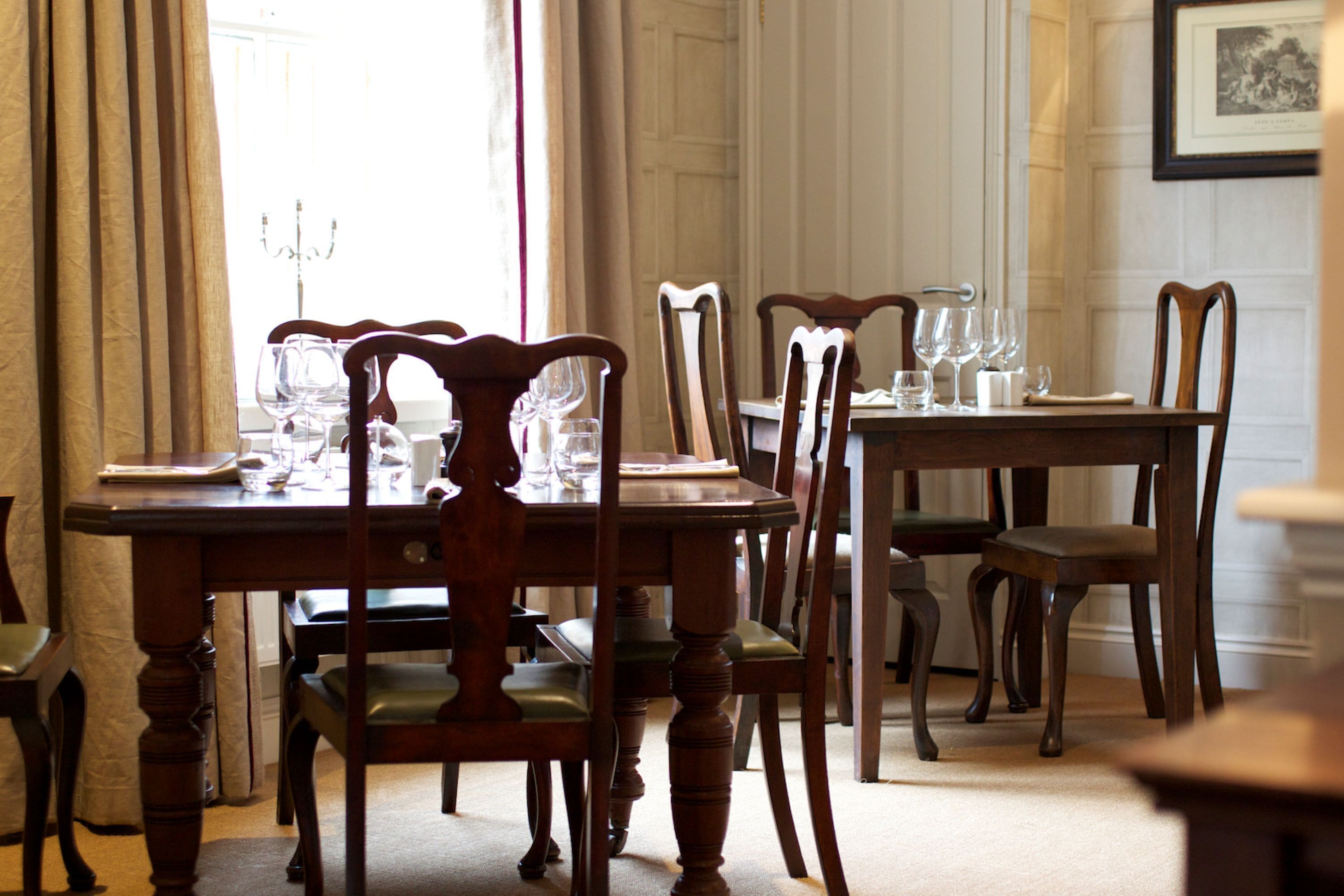 A dining room with a wooden table and chairs, a chandelier, and a framed picture on the wall.
