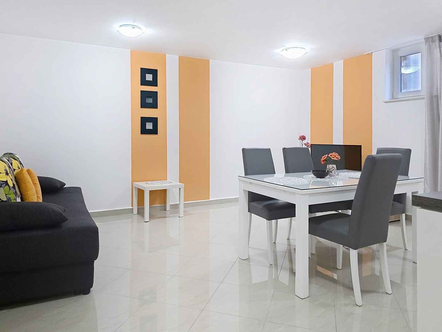 A modern living room with a sofa, a dining table with chairs, and a small side table.