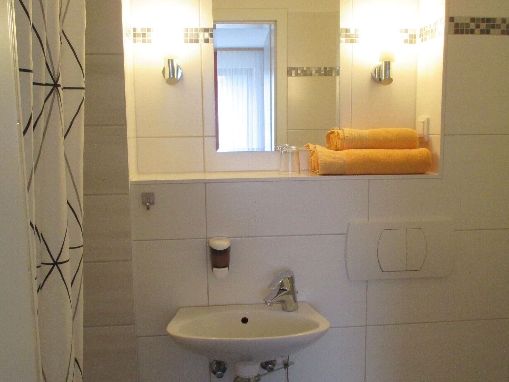 Een badkamer met een wastafel, spiegel en handdoekhouder.