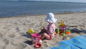 Un niño jugando con juguetes de arena en la playa.