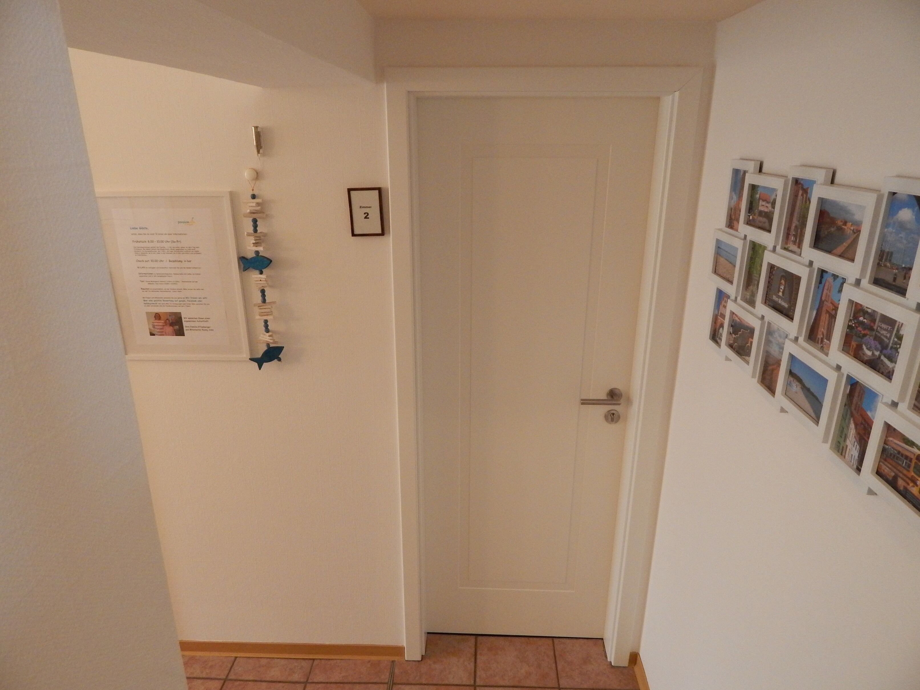 A hallway with a closed door, a wall-mounted photo collage, and a small framed picture.