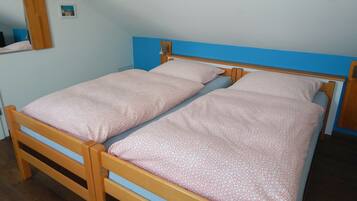 Uma cama de solteiro com estrutura de madeira e cabeceira azul, coberta por um edredom estampado.