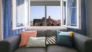 A grey sofa with four cushions in a room with large windows. - The Harmony Rooms Split (Split)