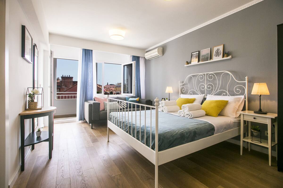Et moderne soveværelse med seng, sengeborde, et skrivebord og et vindue med gardiner.