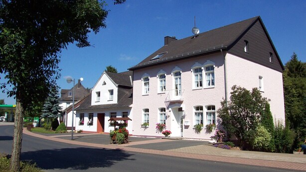A two-story building with a symmetrical facade, a central entrance with a small porch, and a satellite dish on the roof. - Families, groups, cycling, biking, hiking, vacation with dog, short vacation, Kyllradweg, (Stadtkyll)