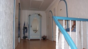 A hallway with a wooden floor, a blue and white staircase, and a decorative mirror cabinet. - Families, groups, cycling, biking, hiking, vacation with dog, short vacation, Kyllradweg, (Stadtkyll)