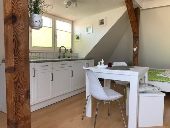 A compact kitchen with white cabinets, a white dining table, and a single white chair. - Lovingly furnished apartment on the top floor (Zwenkau)