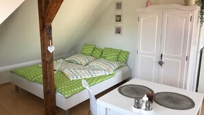 Un dormitorio pequeño y acogedor con cama tipo litera, un escritorio blanco con silla y un armario blanco.