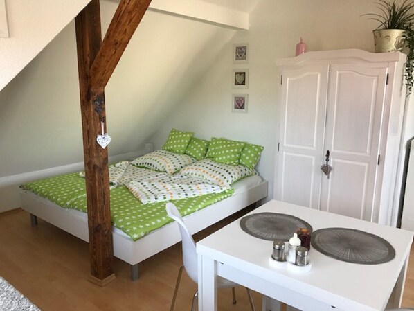 A small, cozy bedroom with a loft bed, a white desk with a chair, and a white wardrobe. - Lovingly furnished apartment on the top floor (Zwenkau)