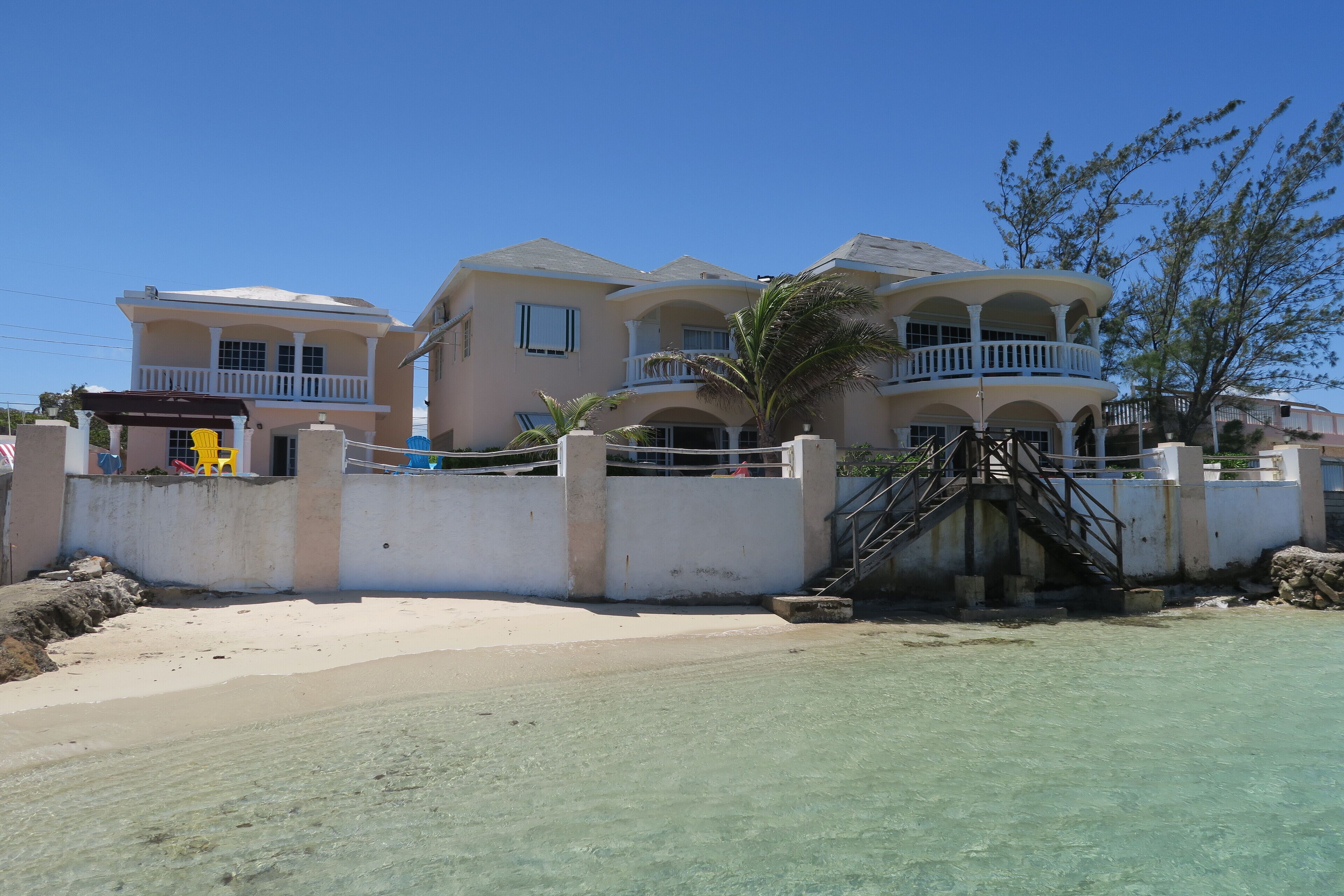 A large, multi-story house with a balcony, located near a beach.