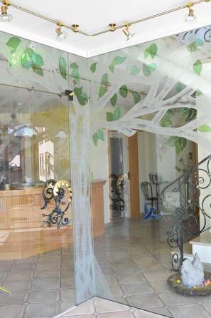 A modern interior with a glass partition, a staircase with metal railings, and a decorative nest with colorful eggs. - Landhotel Gillenfelder Hof (Gillenfeld)