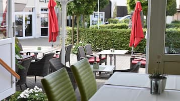 An outdoor seating area with tables and chairs, umbrellas, and a view of a building in the background.