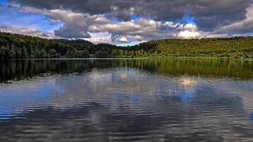 Um lago tranquilo com uma encosta arborizada ao fundo.