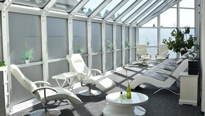 A sunroom with a glass ceiling, white furniture, and potted plants. - Landhotel Gillenfelder Hof (Gillenfeld)