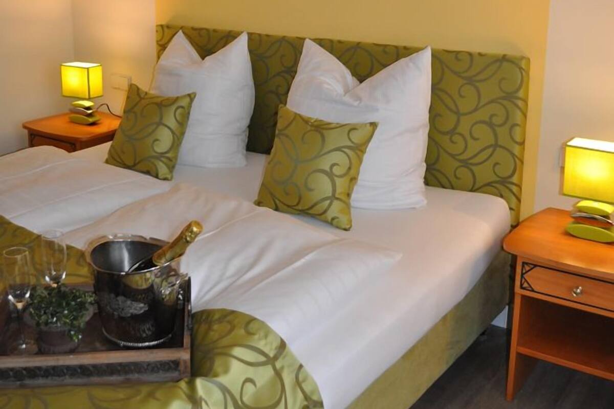 Una habitación de hotel con una cama grande, dos mesitas de noche con lámparas y una obra de arte en la pared.