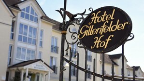 A sign for Hotel Gillenfelder Hof with a traditional European architectural style in the background. - Landhotel Gillenfelder Hof (Gillenfeld)