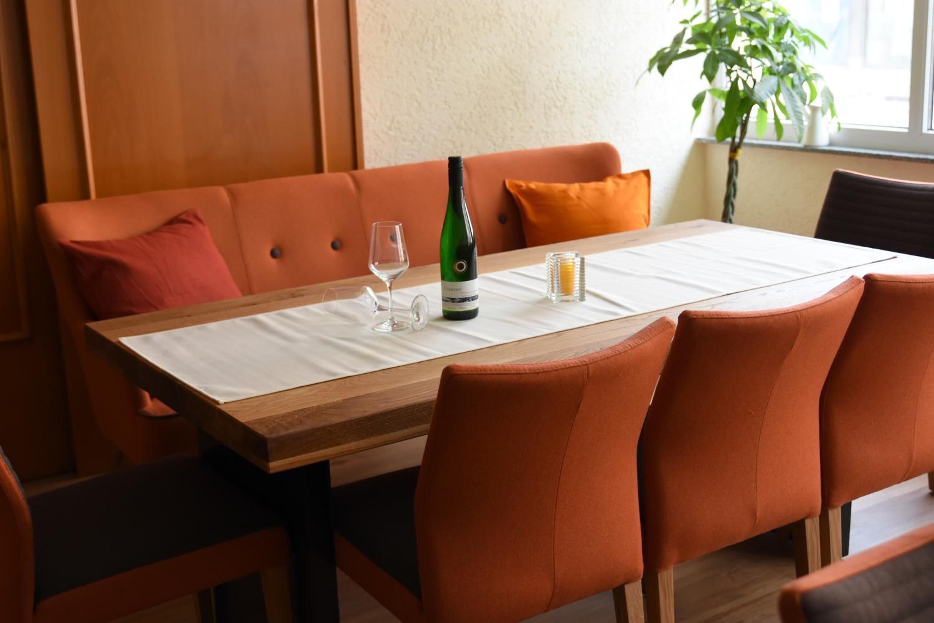 Una mesa de comedor con mantel blanco, una botella de vino y copas.
