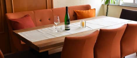 Una mesa de comedor con mantel blanco, una botella de vino y copas.