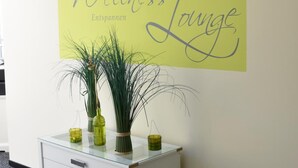 A reception desk with a sign reading "Wellness Lounge" and a decorative plant arrangement. - Landhotel Gillenfelder Hof (Gillenfeld)