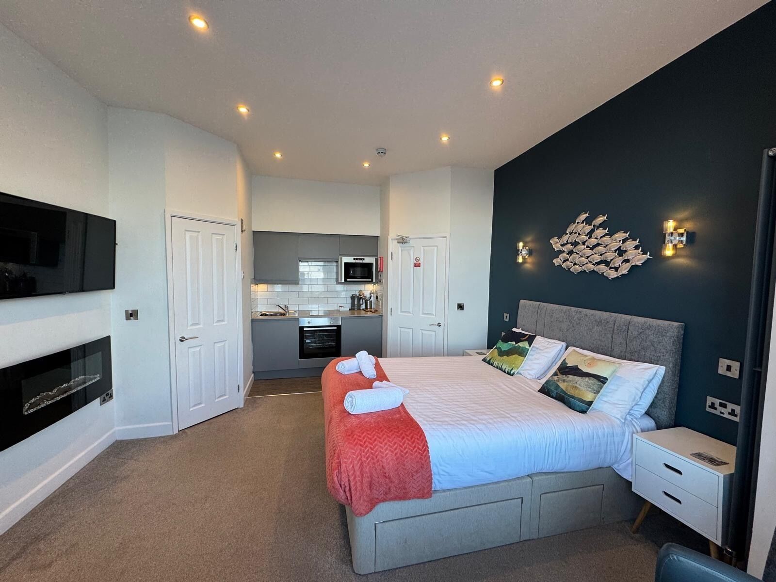 A bedroom with a bed, bedside table, and a TV mounted on the wall.