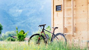 Una cabaña de madera con una bicicleta estacionada afuera, una escalera y un cartel.