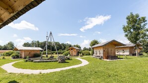 Entorno rústico al aire libre con cabañas de madera, un columpio y una mesa de picnic.