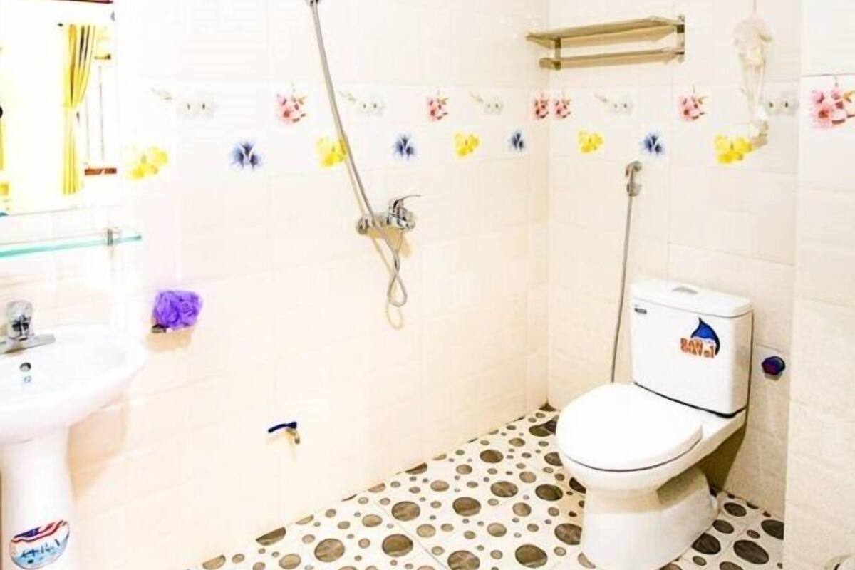 A small bathroom with a toilet, a sink, a shower, and a water heater.