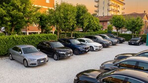 A parking lot with multiple cars, surrounded by trees and buildings.