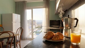A kitchen with a coffee maker, croissants, and a glass of orange juice on a table.