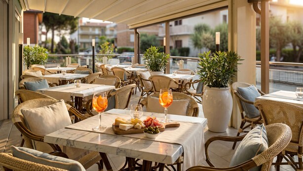 An outdoor seating area with tables and wicker chairs, featuring a view of the cityscape.