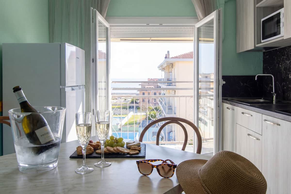 A dining area with a table set for two, featuring a bottle of wine, glasses, and snacks.