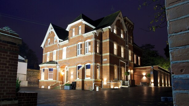 A large, historic brick building with multiple windows and a prominent entrance, illuminated by exterior lights. - The Northgate (Bury St Edmunds)