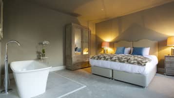 Une chambre à coucher avec un grand lit, une baignoire, une armoire et une table de chevet avec une lampe.