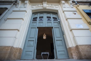 Entrada de un edificio con un gran arco, una lámpara colgante y una pequeña mesa con un florero.