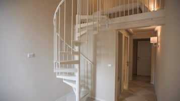 A white spiral staircase leading to a loft bedroom with a small window.