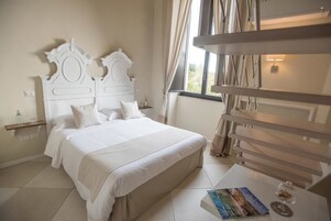 Un dormitorio ordenado con una cama grande, una mesita de noche con un libro y un vaso, y una ventana con cortinas.