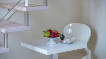 Una mesa blanca con un frutero y un paño doblado.