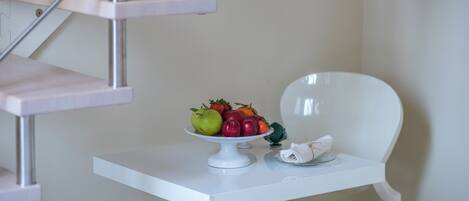 A white table with a fruit bowl and a folded napkin.