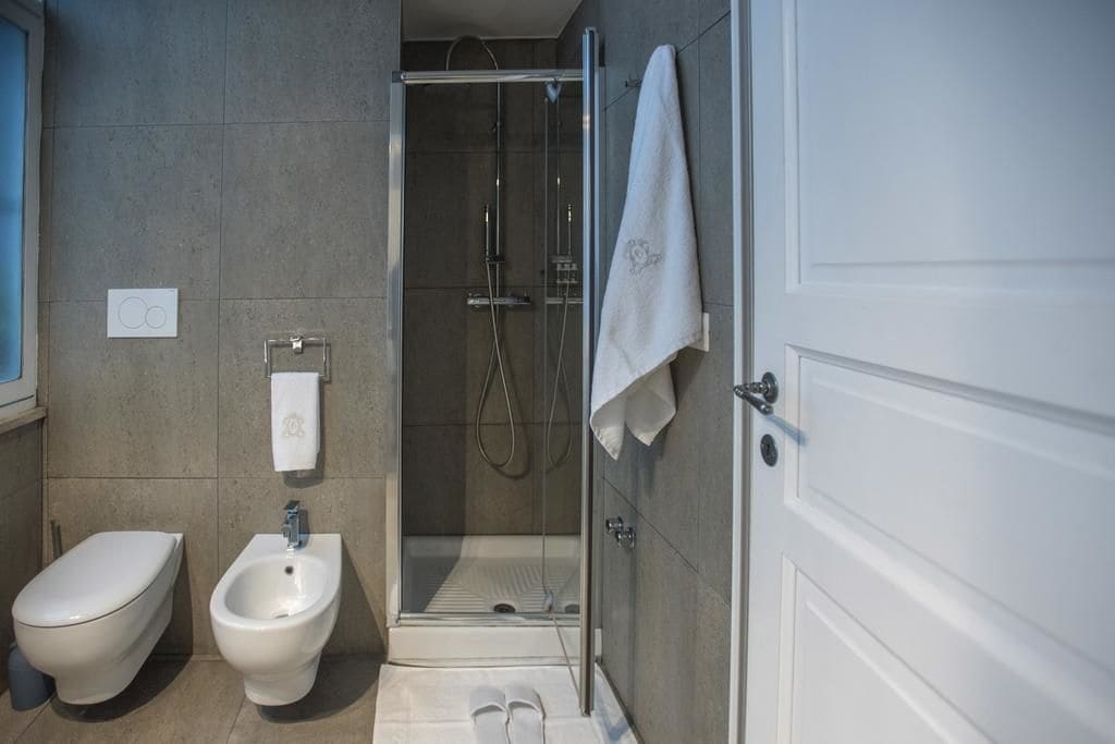 A modern bathroom with a bidet, a shower, and a towel hanging on the wall.